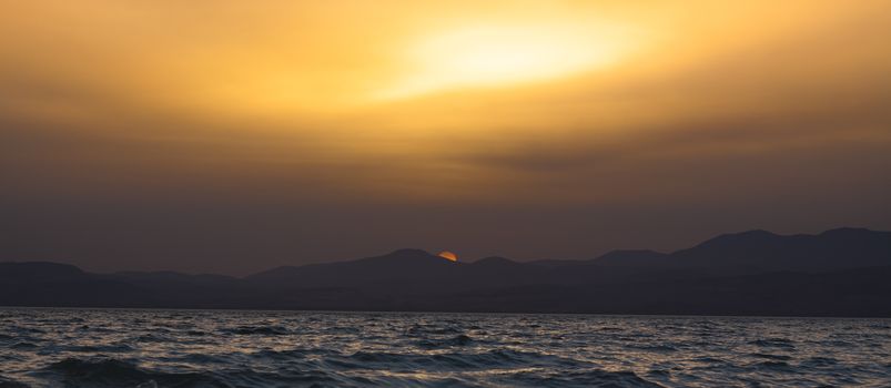 golden  sunset reflection in the sea with mountain in the background