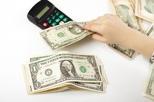 hand separating dollars by type on white background and a black calculator