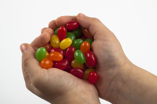 a pair of child hands holding a pile of colored candy