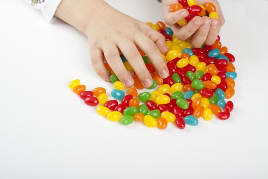 child grabing and holding lot's of colored candy 