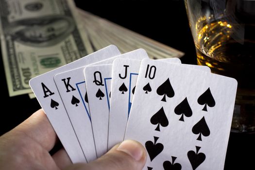 poker playing cards whiskey and some money on a table with reflection