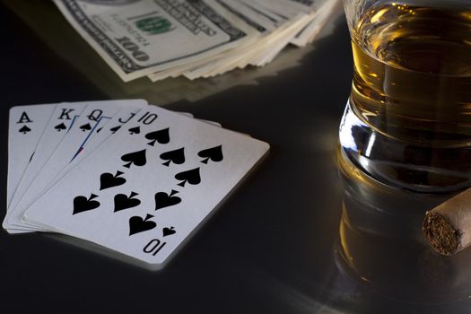 playing card whiskey and some money on a table with reflection