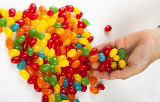 child  holding lot's of colored candy on white background