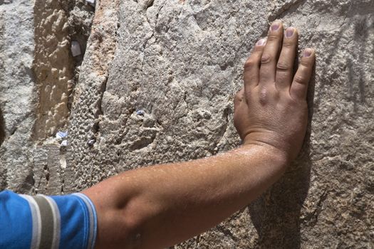 a hand on the western wall wile praying and some notes in the stone