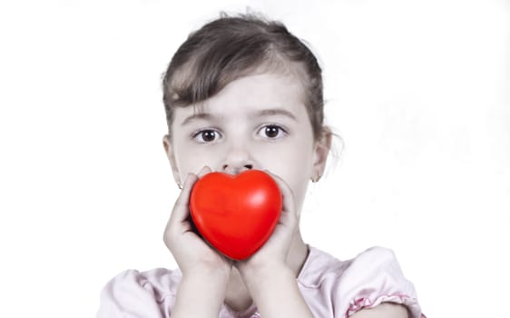 young child holding a red heart on white background