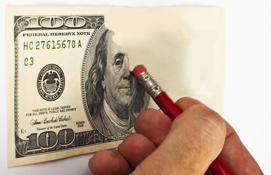 erasing a 100 dollar bill with a red pencil and eraser