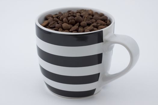 black and white stripe mug full with coffee beans on white background