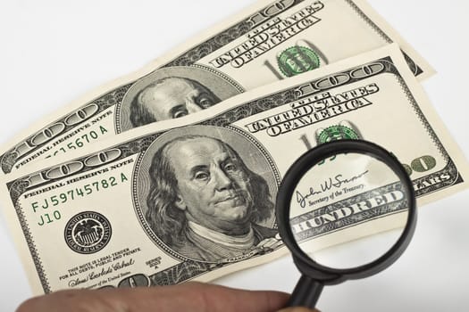 magnifying a dollar bill with a magnifying glass on white background