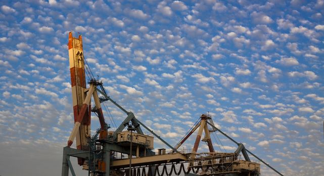 port crane with blue cloudy sky at sunset