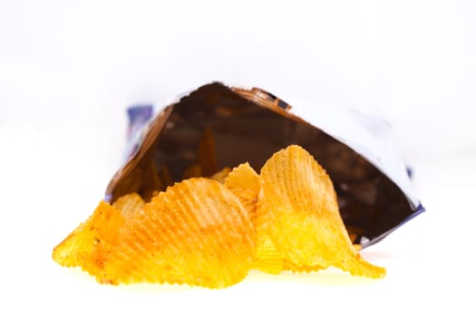 spiced golden chips pile with the bag on white background