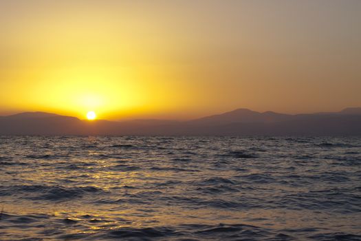 sunset over mountain peek with the sun reflection in the watter