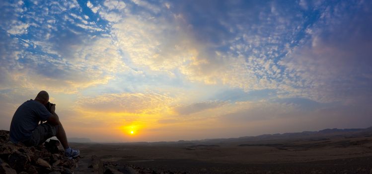 man photographing sunrise in a desert