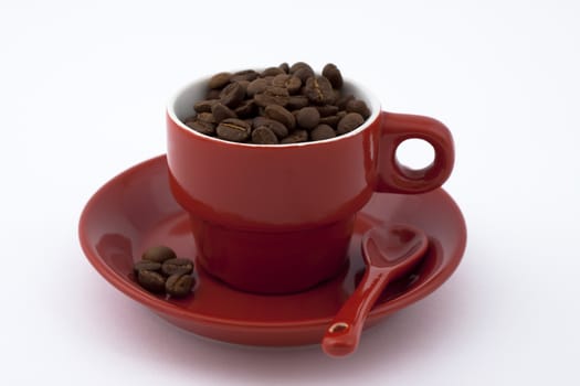 red coffee cup with plate full of coffee beans on white background