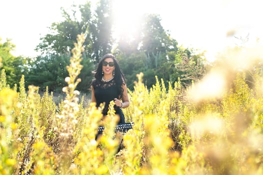 young beautiful fashion girl in yellow field wearing sunglasses