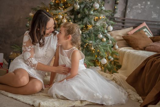 Mother looking kindly on daughter under Christmas tree
