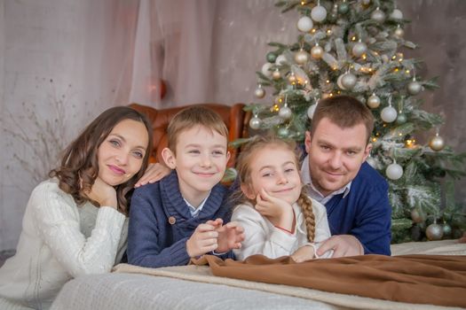Beautiful family of four over cosy Christmas decoration