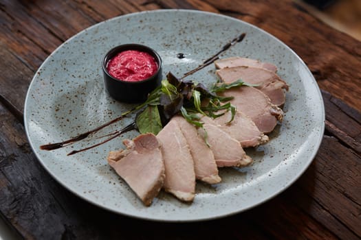 Sliced cold baked pork with herbs on blue plate.