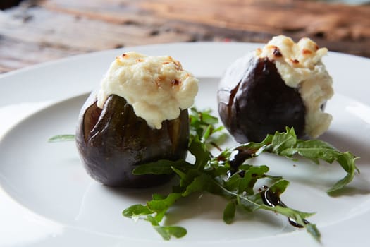 baked figs with goat cheese on wooden table.