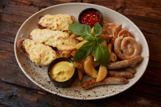 Grilled assorted sausages with French fries, bruschettes with cheese and sauces