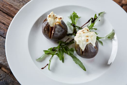 baked figs with goat cheese on wooden table.