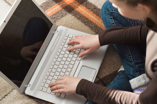 Top view of young teen girl couch prepares report on business lesson, corrects mistakes, keyboards on laptop computer, searches information. Student does homework task