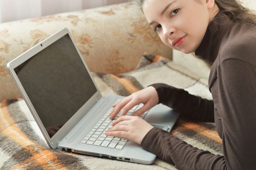 Closeup Hands of pretty young girl lying in bed and using computer at home. Beautiful blonde woman working on a laptop in her bed in pajamas, smiling. Girl blogger is typing for a fresh post