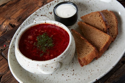 Traditional Ukrainian Russian borscht with white beans on the bowl. Plate of red beet root soup borsch on black rustick table. Beetroot soup Top view. Traditional Ukraine food cuisine.