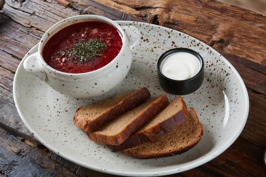 Traditional Ukrainian Russian borscht with white beans on the bowl. Plate of red beet root soup borsch on black rustick table. Beetroot soup Top view. Traditional Ukraine food cuisine.