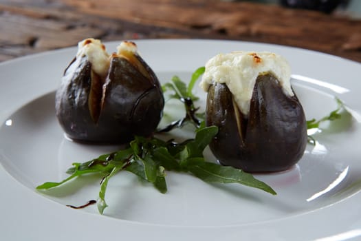 baked figs with goat cheese on wooden table.