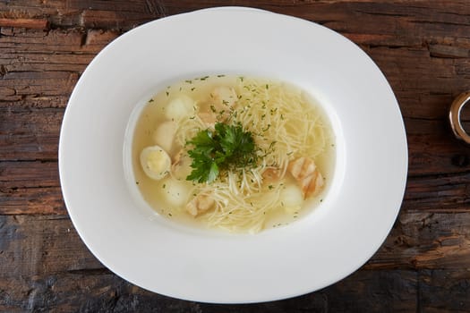 Chicken soup with noodles and vegetables in white bowl.