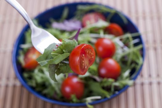 green salad with cherry tomato on a fork