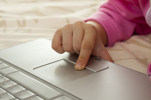 little girl fingers on a  silver laptop's trackpad