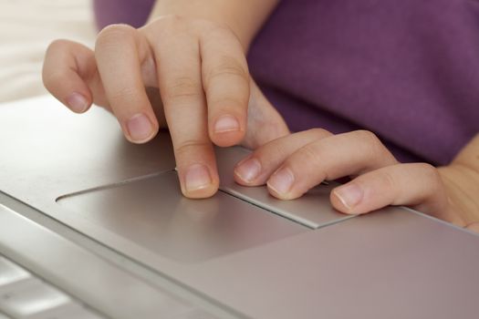 little girl fingers on a  silver laptop's trackpad