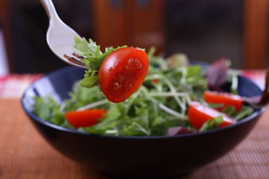 green salad with cherry tomato on a fork