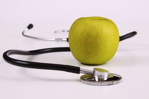green apple with a stethoscope on white background
