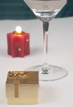 romantic proposal theme with a golden ring box a shampain glass and a red candle with flame