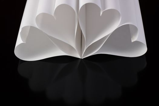 white paper hearts on black table with reflection