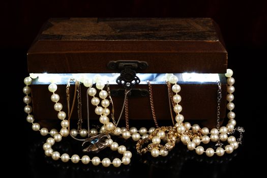 tresure chest with open lid light from within and jewelry with reflection