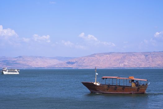 two tourist boats on the sea of galilea with bolan hights in the background