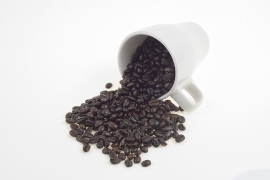 coffee beans falling from a white mug