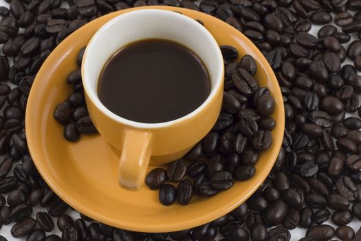 orange coffee mug and plate on coffee beans