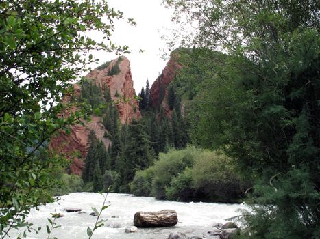 mountain heart in Kyrgyzstan between trees and a stormy rive              