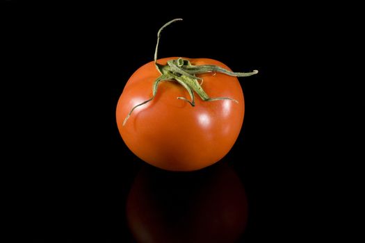 red tomato on blac background with reflection