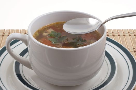 vegetable soup in a white bowl and a spoon