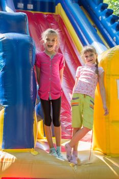 Two joyful girls stand at the entrance to a large inflatable trampoline