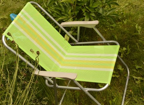 The camping chair is set in the garden on the grass