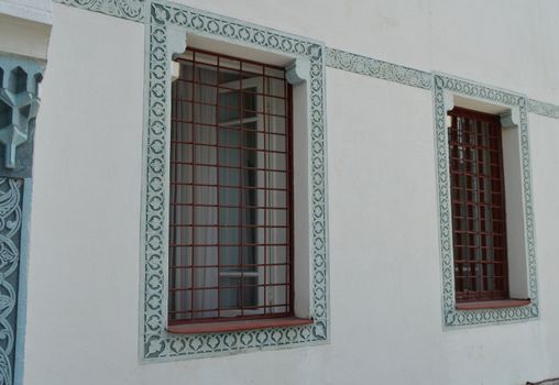 White wall, window with bars and blue Oriental ornament, traditional Arabic style.