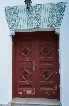 Old brown wooden door with dark blue Oriental designs.