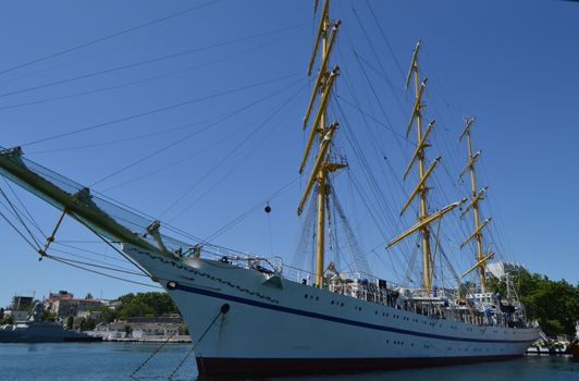 Old yacht with lowered sails moored in the port.