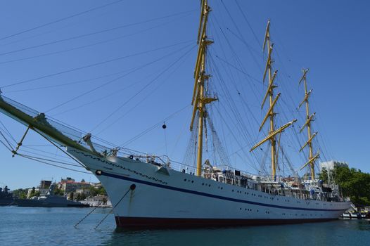 Old yacht with lowered sails moored in the port.